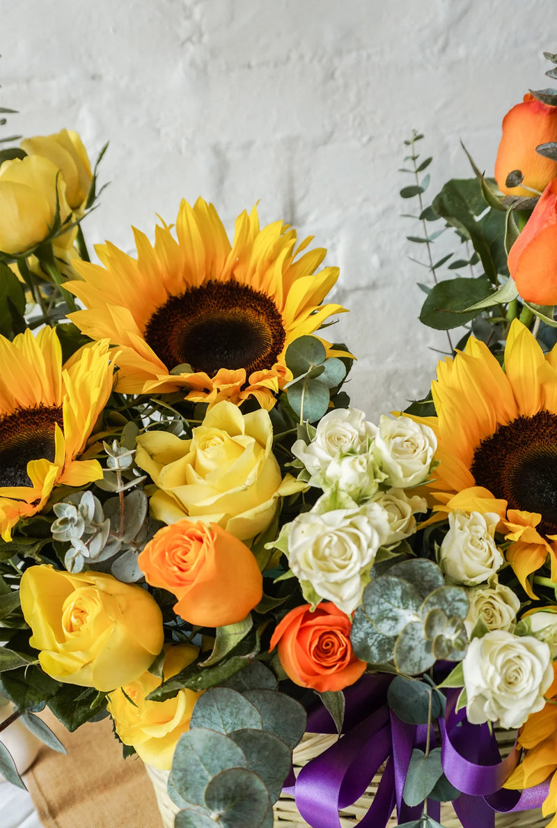 Abril, colorido arreglo floral en canasta con girasoles