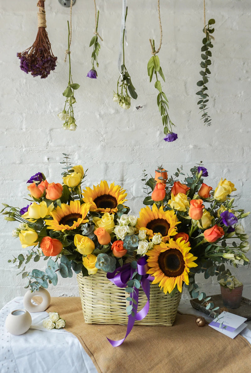 Abril, colorido arreglo floral en canasta con girasoles